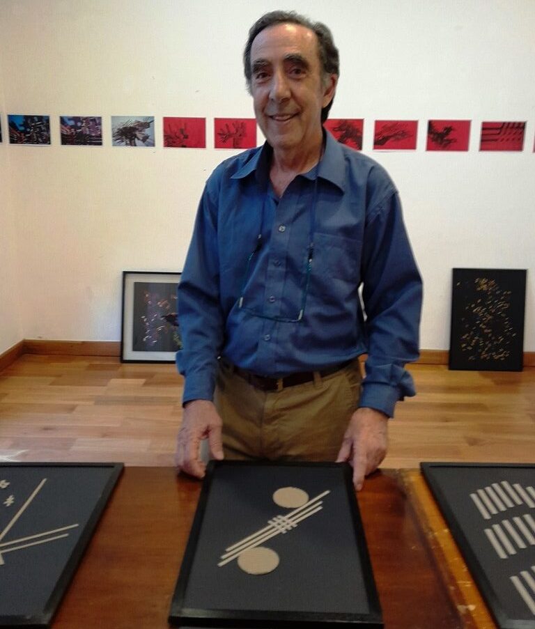 Donato Marrero junto a su serie de formas sobre fondo negro, en el ICE